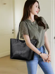 Detail of black patchwork leather tote bag with geometric panels and slim shoulder straps