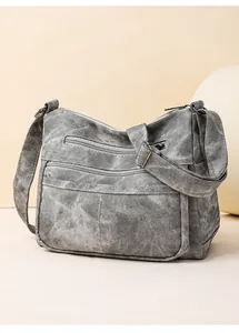Détail du sac bandoulière gris en toile délavée avec plusieurs poches zippées