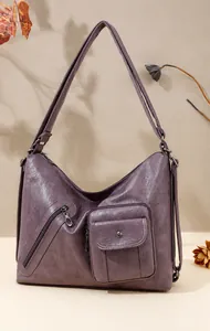 Detail view of purple faux leather bag showing multi-layered pockets and zipper texture