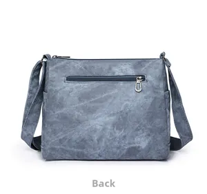 Vue arrière du sac à bandoulière en toile bleu-gris avec poche zippée et latérales