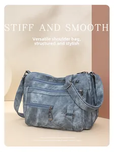 Detail of multi-pocket vintage washed blue denim crossbody bag with adjustable strap