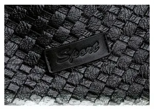 Close-up of black woven texture and Sport embossed leather patch on the tote bag