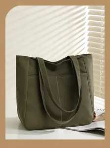 Detail of olive green tote bag with contrast stitching and dual front pockets