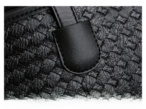 Detailed macro view of woven leather texture and precision stitching on black tote bag