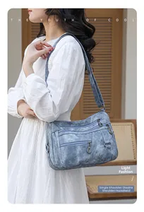 Close-up of blue retro soft leather handbag featuring multiple functional zipper pockets