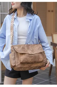 Detail of vintage brown PU leather messenger bag with geometric patterned wide strap