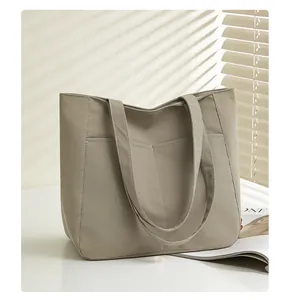 Detailed view of khaki tote bag featuring dual front pockets and premium nylon texture