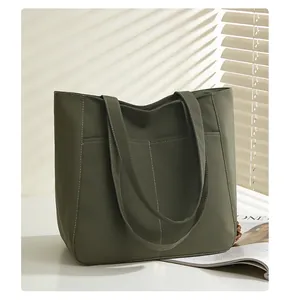 Detail view of large dark green tote bag featuring front pockets with contrast stitching