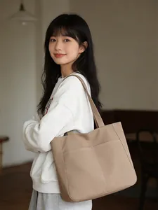 Detail of light brown tote bag featuring dual front pockets and white contrast stitching
