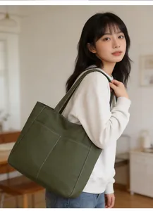 Detail of army green canvas tote bag showing white contrast stitching and front pocket