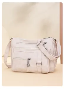 Detail of soft cream PU leather crossbody bag with multiple zippers and gunmetal hardware