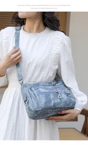 Detail view of a vintage blue crossbody bag featuring multiple zippers and washed texture