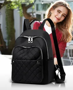 Detail view of black nylon backpack featuring quilted front pocket and silver dual zippers