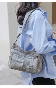 Detail of vintage washed multi-zipper leather shoulder bag with adjustable strap on model
