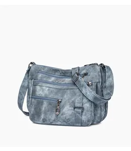 Detail view of washed blue crossbody bag with multi-layer zipper pockets and adjustable strap