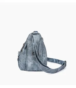 Detail view of washed blue shoulder bag featuring multiple zippered pockets and textured finish