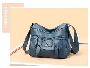 Nahaufnahme der dunkelblauen Kunstledertasche mit Reißverschlüssen und Metall-Logo