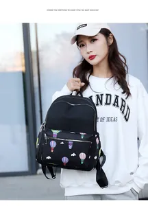 Outdoor lifestyle view of women's black backpack featuring a colorful hot air balloon print