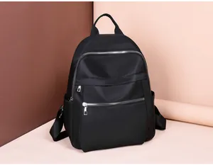 Macro detail of the smooth black oxford fabric and silver zippers on a backpack