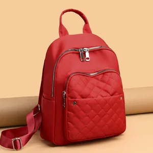 Red nylon quilted backpack for women featuring multiple silver zippers and top handle