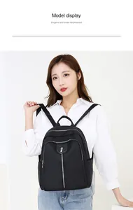 Detail view of a black Oxford cloth backpack with silver zippers and side pockets