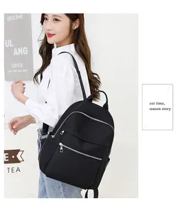 Close-up of minimalist black Oxford fabric backpack showing silver metal zipper details