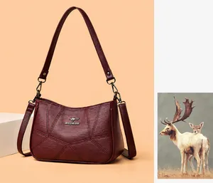Close-up of wine red soft leather handbag featuring V-shaped stitching and metal kangaroo icon