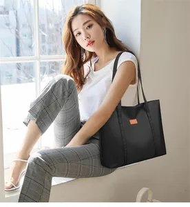 Close-up of lightweight black fabric tote bag with long handles and orange brand label