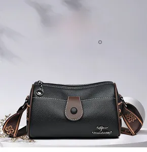 Detail of black lychee leather crossbody bag with jacquard strap and metal kangaroo logo