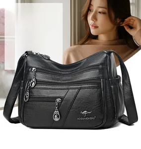 Detail of black crossbody bag with multiple zippers and pebble grain faux leather texture