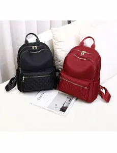 Detalle de mochilas de nailon acolchado en negro y burdeos con cremalleras doradas