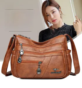 Macro shot of brown pebble texture leather on multi-zipper shoulder bag with logo