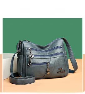 Detail shot of multi-layered silver zippers and round metal charms on blue crossbody bag