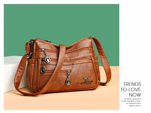 Detail view of brown leather bag featuring multiple front zippers and a gold logo