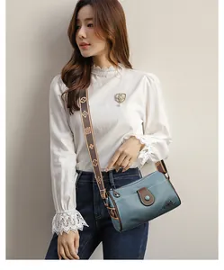 Detail of grey-blue grain leather crossbody bag featuring floral jacquard wide strap