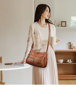 Detail of a brown multi-pocket crossbody bag with soft leather texture and zipper pockets