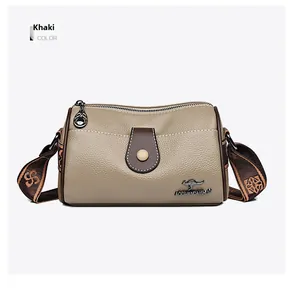 Close-up of khaki leather crossbody bag with vintage pattern strap and metal logo