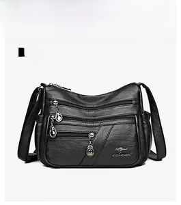 Front detail of black leather crossbody bag featuring triple zip pockets and heart charms