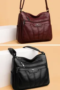 Detalle de bolsos bandolera rojos y negros con múltiples compartimentos con cremallera