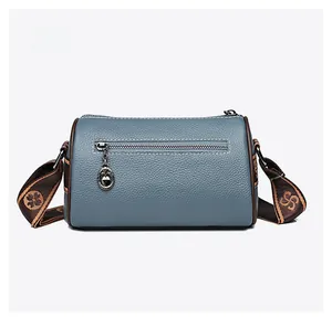 Rear view of blue lychee grain leather cylinder bag with metal zipper and jacquard strap