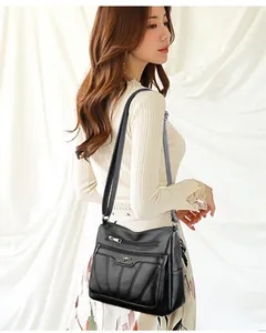 Detalle del bolso negro con bolsillos de cremallera y diseño de costuras bordadas