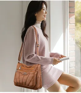 Detalle de bolso vintage de cuero marrón con múltiples cremalleras y logotipo metálico