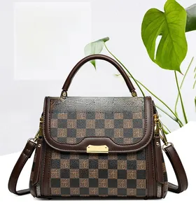 Detailed view of brown checkered pattern with logo print and golden hardware on handbag