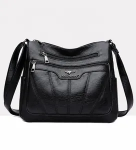 Detalle frontal del bolso de hombro en cuero PU negro con cremalleras y logo metálico