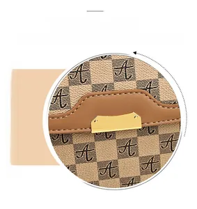 Close-up of beige checkerboard pattern with gold metal buckle and brown leather trim
