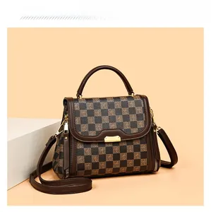 Detail of checkered pattern on brown handbag with golden buckle and sleek leather handle