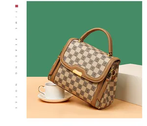Detail of checkered handbag with brown leather handle and elegant gold metal clasp