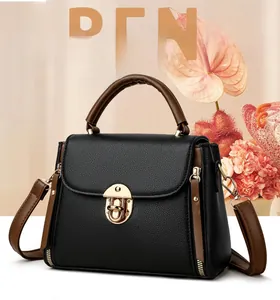 Détail du sac bandoulière en cuir noir avec serrure dorée et poignée marron