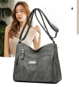 Close-up of charcoal grey shoulder bag showing multiple zipper pockets and white stitching