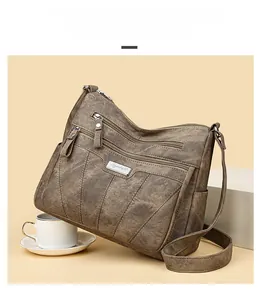 Detail of a brown multi-pocket crossbody bag with bucket trapezoid shape and zippers